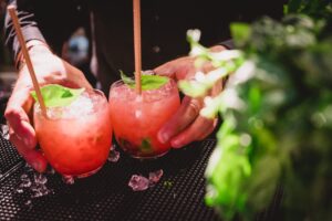 A pair of cocktail being picked up from the bar