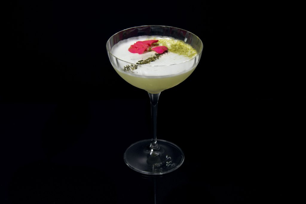 A Pink Geisha cocktail in a bowl-shaped stemmed glass.