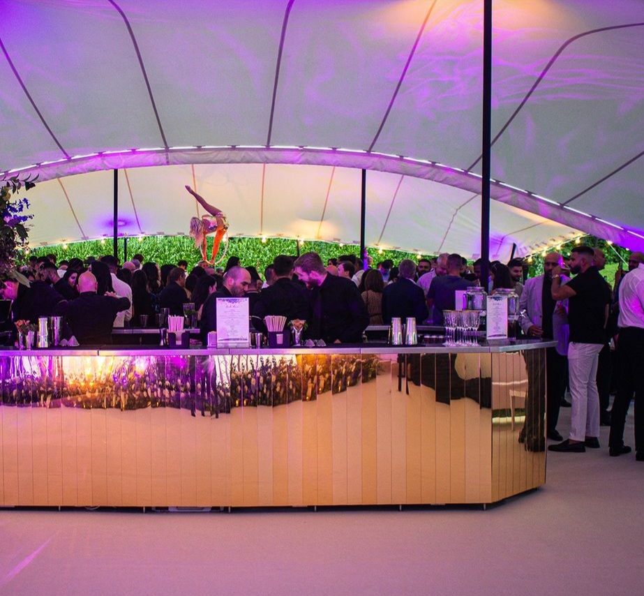 A corporate social events with a crowd of people standing at a mirrored bar